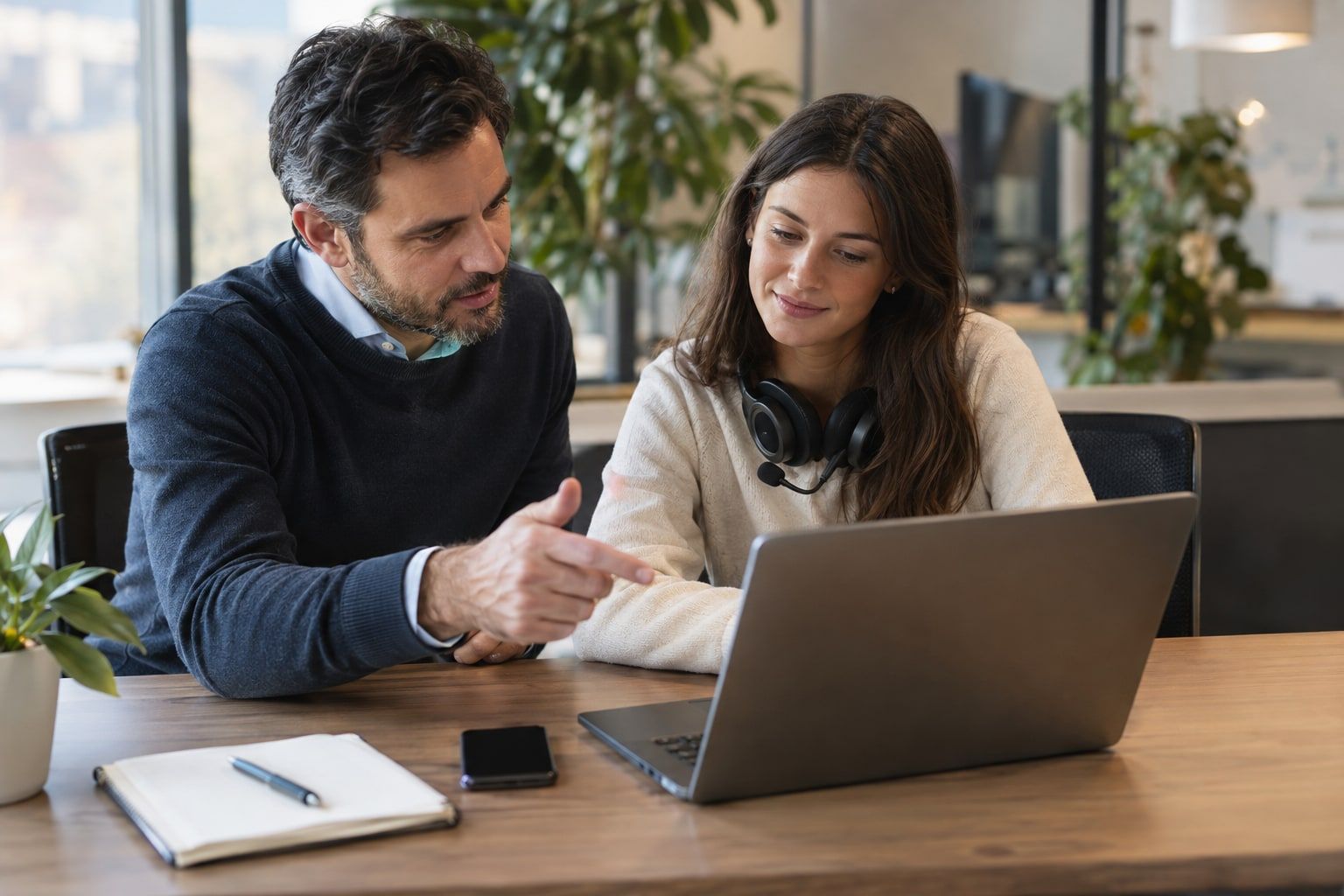 A sales manager coaching a sales rep one-on-one at a desk